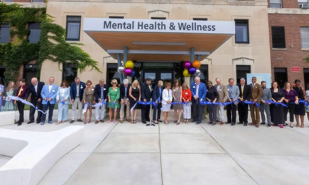 A crowd gathers to cut the ribbon on a new pediatric behavioral health urgent care center.